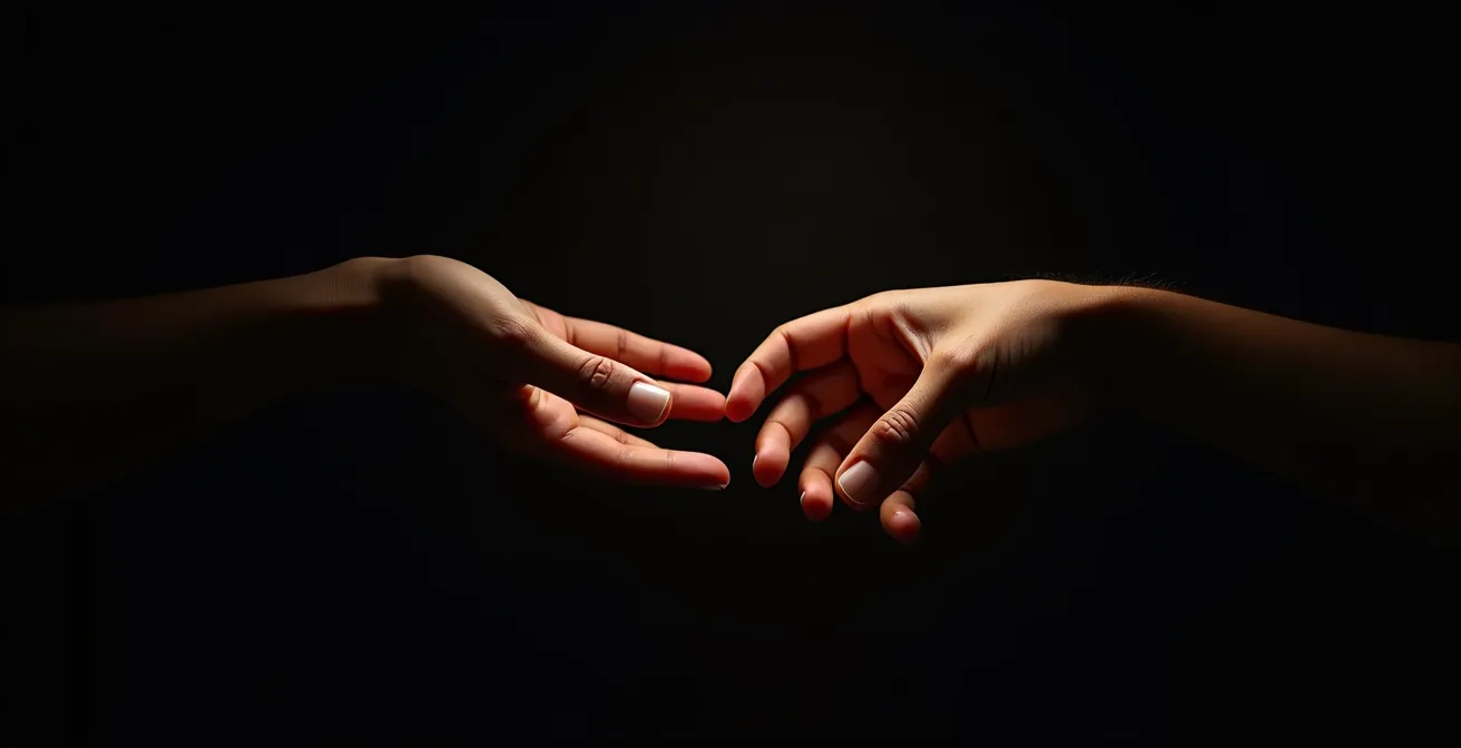 Zwei Hände strecken sich in einer unterstützenden Geste nacheinander aus, dramatisch beleuchtet vor dunklem Hintergrund.